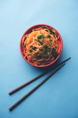 Schezwan erişte veya sebze Hakka erişte veya chow mein tahta çubukla bir kase veya plaka servis popüler Hint-Çin yemek tarifleri, var. seçici odak