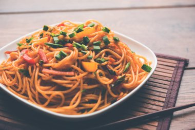 Schezwan erişte veya sebze Hakka erişte veya chow mein tahta çubukla bir kase veya plaka servis popüler Hint-Çin yemek tarifleri, var. seçici odak