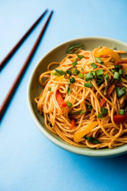 Schezwan erişte veya sebze Hakka erişte veya chow mein tahta çubukla bir kase veya plaka servis popüler Hint-Çin yemek tarifleri, var. seçici odak