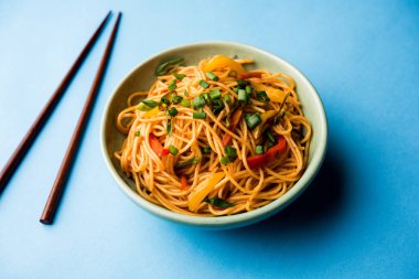 Schezwan erişte veya sebze Hakka erişte veya chow mein tahta çubukla bir kase veya plaka servis popüler Hint-Çin yemek tarifleri, var. seçici odak