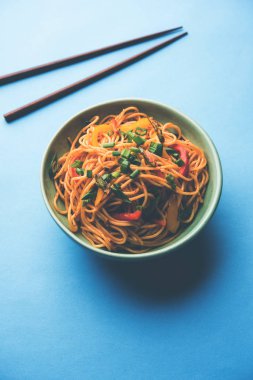 Schezwan erişte veya sebze Hakka erişte veya chow mein tahta çubukla bir kase veya plaka servis popüler Hint-Çin yemek tarifleri, var. seçici odak