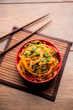 Schezwan erişte veya sebze Hakka erişte veya chow mein tahta çubukla bir kase veya plaka servis popüler Hint-Çin yemek tarifleri, var. seçici odak