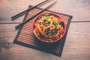 Schezwan erişte veya sebze Hakka erişte veya chow mein tahta çubukla bir kase veya plaka servis popüler Hint-Çin yemek tarifleri, var. seçici odak