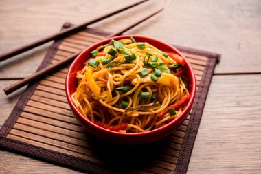 Schezwan erişte veya sebze Hakka erişte veya chow mein tahta çubukla bir kase veya plaka servis popüler Hint-Çin yemek tarifleri, var. seçici odak