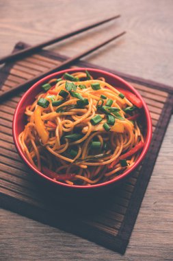 Schezwan erişte veya sebze Hakka erişte veya chow mein tahta çubukla bir kase veya plaka servis popüler Hint-Çin yemek tarifleri, var. seçici odak