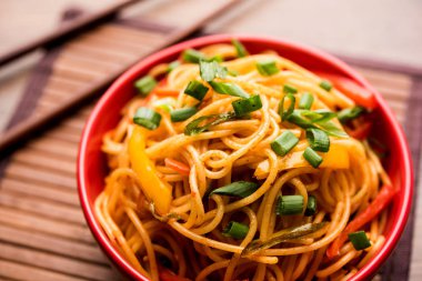 Schezwan erişte veya sebze Hakka erişte veya chow mein tahta çubukla bir kase veya plaka servis popüler Hint-Çin yemek tarifleri, var. seçici odak