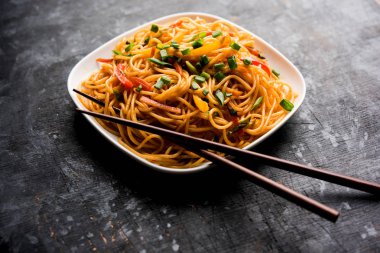 Schezwan erişte veya sebze Hakka erişte veya chow mein tahta çubukla bir kase veya plaka servis popüler Hint-Çin yemek tarifleri, var. seçici odak