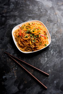 Schezwan erişte veya sebze Hakka erişte veya chow mein tahta çubukla bir kase veya plaka servis popüler Hint-Çin yemek tarifleri, var. seçici odak