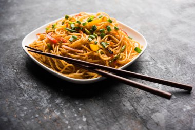 Schezwan erişte veya sebze Hakka erişte veya chow mein tahta çubukla bir kase veya plaka servis popüler Hint-Çin yemek tarifleri, var. seçici odak