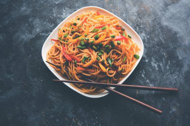 Schezwan erişte veya sebze Hakka erişte veya chow mein tahta çubukla bir kase veya plaka servis popüler Hint-Çin yemek tarifleri, var. seçici odak