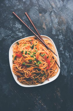 Schezwan erişte veya sebze Hakka erişte veya chow mein tahta çubukla bir kase veya plaka servis popüler Hint-Çin yemek tarifleri, var. seçici odak