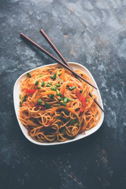 Schezwan erişte veya sebze Hakka erişte veya chow mein tahta çubukla bir kase veya plaka servis popüler Hint-Çin yemek tarifleri, var. seçici odak