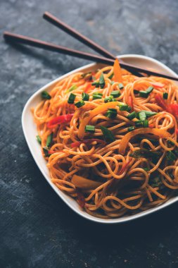 Schezwan erişte veya sebze Hakka erişte veya chow mein tahta çubukla bir kase veya plaka servis popüler Hint-Çin yemek tarifleri, var. seçici odak