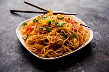Schezwan erişte veya sebze Hakka erişte veya chow mein tahta çubukla bir kase veya plaka servis popüler Hint-Çin yemek tarifleri, var. seçici odak