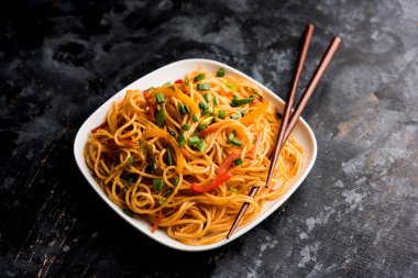 Schezwan erişte veya sebze Hakka erişte veya chow mein tahta çubukla bir kase veya plaka servis popüler Hint-Çin yemek tarifleri, var. seçici odak