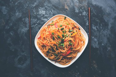 Schezwan erişte veya sebze Hakka erişte veya chow mein tahta çubukla bir kase veya plaka servis popüler Hint-Çin yemek tarifleri, var. seçici odak