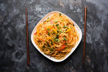 Schezwan erişte veya sebze Hakka erişte veya chow mein tahta çubukla bir kase veya plaka servis popüler Hint-Çin yemek tarifleri, var. seçici odak