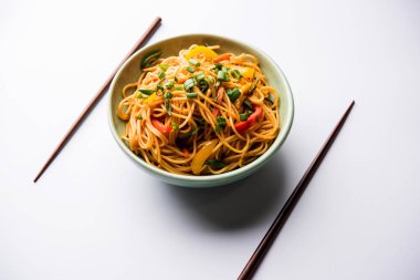 Schezwan erişte veya sebze Hakka erişte veya chow mein tahta çubukla bir kase veya plaka servis popüler Hint-Çin yemek tarifleri, var. seçici odak