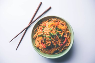 Schezwan erişte veya sebze Hakka erişte veya chow mein tahta çubukla bir kase veya plaka servis popüler Hint-Çin yemek tarifleri, var. seçici odak