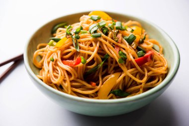 Schezwan erişte veya sebze Hakka erişte veya chow mein tahta çubukla bir kase veya plaka servis popüler Hint-Çin yemek tarifleri, var. seçici odak