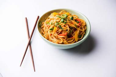 Schezwan erişte veya sebze Hakka erişte veya chow mein tahta çubukla bir kase veya plaka servis popüler Hint-Çin yemek tarifleri, var. seçici odak