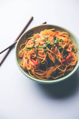 Schezwan erişte veya sebze Hakka erişte veya chow mein tahta çubukla bir kase veya plaka servis popüler Hint-Çin yemek tarifleri, var. seçici odak