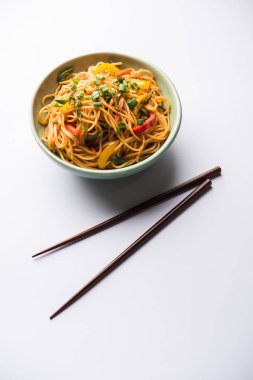 Schezwan erişte veya sebze Hakka erişte veya chow mein tahta çubukla bir kase veya plaka servis popüler Hint-Çin yemek tarifleri, var. seçici odak