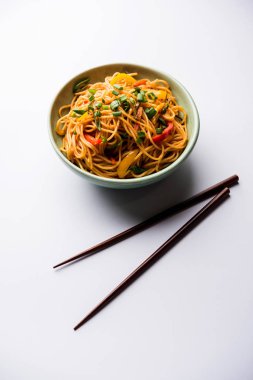 Schezwan erişte veya sebze Hakka erişte veya chow mein tahta çubukla bir kase veya plaka servis popüler Hint-Çin yemek tarifleri, var. seçici odak