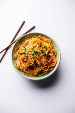 Schezwan erişte veya sebze Hakka erişte veya chow mein tahta çubukla bir kase veya plaka servis popüler Hint-Çin yemek tarifleri, var. seçici odak