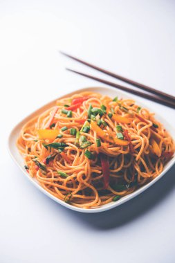 Schezwan erişte veya sebze Hakka erişte veya chow mein tahta çubukla bir kase veya plaka servis popüler Hint-Çin yemek tarifleri, var. seçici odak