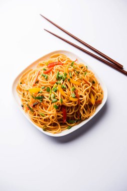 Schezwan erişte veya sebze Hakka erişte veya chow mein tahta çubukla bir kase veya plaka servis popüler Hint-Çin yemek tarifleri, var. seçici odak