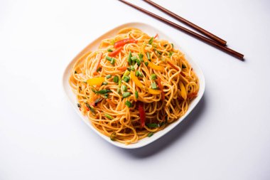 Schezwan erişte veya sebze Hakka erişte veya chow mein tahta çubukla bir kase veya plaka servis popüler Hint-Çin yemek tarifleri, var. seçici odak
