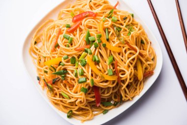 Schezwan erişte veya sebze Hakka erişte veya chow mein tahta çubukla bir kase veya plaka servis popüler Hint-Çin yemek tarifleri, var. seçici odak