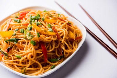 Schezwan erişte veya sebze Hakka erişte veya chow mein tahta çubukla bir kase veya plaka servis popüler Hint-Çin yemek tarifleri, var. seçici odak
