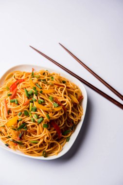 Schezwan erişte veya sebze Hakka erişte veya chow mein tahta çubukla bir kase veya plaka servis popüler Hint-Çin yemek tarifleri, var. seçici odak