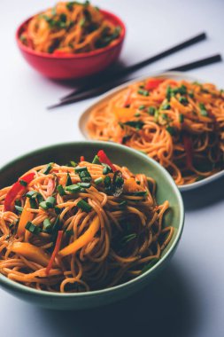 Schezwan erişte veya sebze Hakka erişte veya chow mein tahta çubukla bir kase veya plaka servis popüler Hint-Çin yemek tarifleri, var. seçici odak