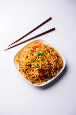 Schezwan erişte veya sebze Hakka erişte veya chow mein tahta çubukla bir kase veya plaka servis popüler Hint-Çin yemek tarifleri, var. seçici odak