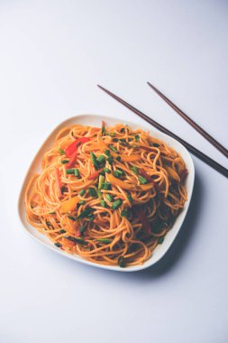 Schezwan erişte veya sebze Hakka erişte veya chow mein tahta çubukla bir kase veya plaka servis popüler Hint-Çin yemek tarifleri, var. seçici odak