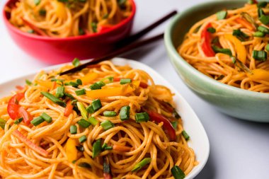 Schezwan erişte veya sebze Hakka erişte veya chow mein tahta çubukla bir kase veya plaka servis popüler Hint-Çin yemek tarifleri, var. seçici odak