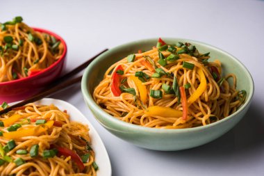 Schezwan erişte veya sebze Hakka erişte veya chow mein tahta çubukla bir kase veya plaka servis popüler Hint-Çin yemek tarifleri, var. seçici odak