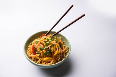 Schezwan erişte veya sebze Hakka erişte veya chow mein tahta çubukla bir kase veya plaka servis popüler Hint-Çin yemek tarifleri, var. seçici odak