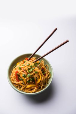 Schezwan erişte veya sebze Hakka erişte veya chow mein tahta çubukla bir kase veya plaka servis popüler Hint-Çin yemek tarifleri, var. seçici odak