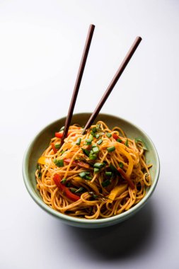 Schezwan erişte veya sebze Hakka erişte veya chow mein tahta çubukla bir kase veya plaka servis popüler Hint-Çin yemek tarifleri, var. seçici odak