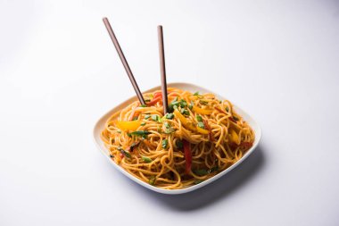 Schezwan erişte veya sebze Hakka erişte veya chow mein tahta çubukla bir kase veya plaka servis popüler Hint-Çin yemek tarifleri, var. seçici odak