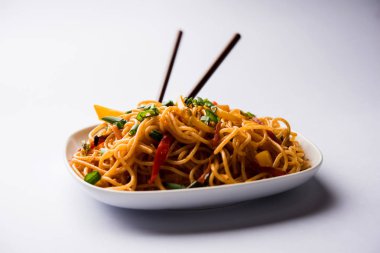 Schezwan erişte veya sebze Hakka erişte veya chow mein tahta çubukla bir kase veya plaka servis popüler Hint-Çin yemek tarifleri, var. seçici odak