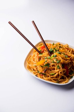 Schezwan erişte veya sebze Hakka erişte veya chow mein tahta çubukla bir kase veya plaka servis popüler Hint-Çin yemek tarifleri, var. seçici odak