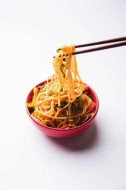 Schezwan erişte veya sebze Hakka erişte veya chow mein tahta çubukla bir kase veya plaka servis popüler Hint-Çin yemek tarifleri, var. seçici odak