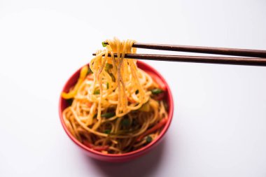 Schezwan erişte veya sebze Hakka erişte veya chow mein tahta çubukla bir kase veya plaka servis popüler Hint-Çin yemek tarifleri, var. seçici odak