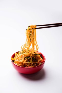 Schezwan erişte veya sebze Hakka erişte veya chow mein tahta çubukla bir kase veya plaka servis popüler Hint-Çin yemek tarifleri, var. seçici odak