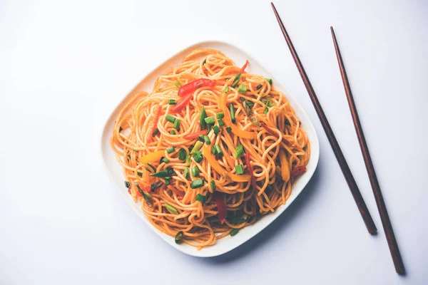 Schezwan erişte veya sebze Hakka erişte veya chow mein tahta çubukla bir kase veya plaka servis popüler Hint-Çin yemek tarifleri, var. seçici odak